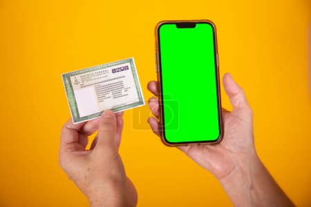 Foto de Mano con tarjeta de identidad brasileña, RG, smartphone con pantalla verde - Imagen libre de derechos