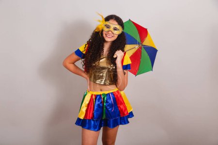 Téléchargez les photos : Jeune adolescente, brésilienne, avec des vêtements frevo, carnaval. tenant un parapluie frevo. mains sur la taille. - en image libre de droit