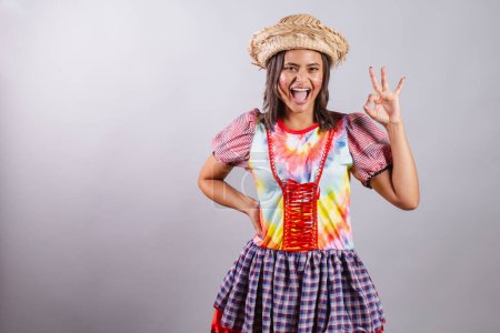 Foto de Mujer brasileña vistiendo ropa de campo, fiesta So Joo, fiesta Junina. ok signo con los dedos. - Imagen libre de derechos