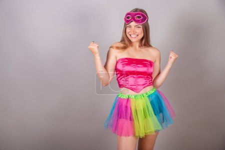 Téléchargez les photos : Femme blonde brésilienne vêtue de vêtements de carnaval rose. portant un masque, célébrant. - en image libre de droit