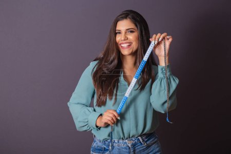 Photo for Horizontal photo. Beautiful Brazilian woman, with casual clothes, Jeans and green shirt. nutritionist holding measuring tape. - Royalty Free Image