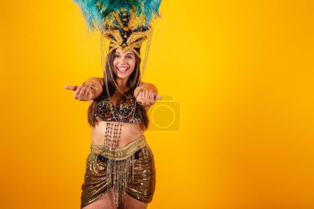Photo for Beautiful Brazilian woman in golden carnival clothes, wearing carnival dancer feather crown. inviting with hands - Royalty Free Image