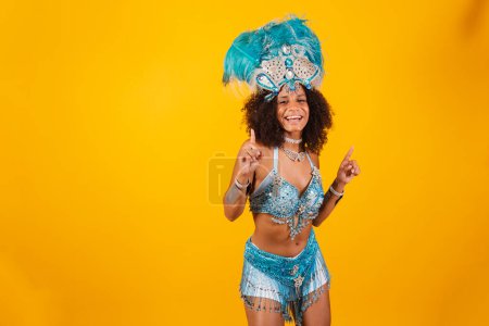 Foto de Mujer negra reina de la escuela brasileña de samba, con ropa de carnaval azul y corona de plumas. bailando. - Imagen libre de derechos