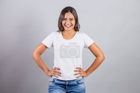 Foto de Hermosa mujer brasileña. denim y blanco. Manos en las caderas, sonriendo. - Imagen libre de derechos