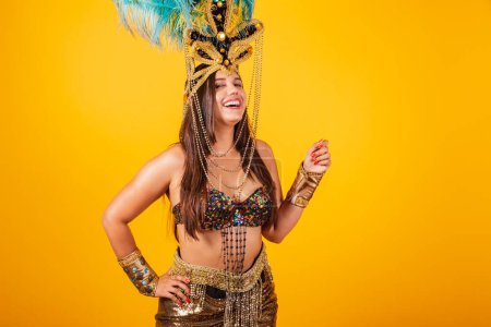 Photo for Beautiful Brazilian woman in golden carnival clothes, wearing carnival dancer feather crown. - Royalty Free Image