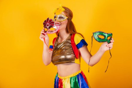 Téléchargez les photos : Rousse brésilienne, avec des vêtements de carnaval, frevo, et parasol coloré. portant un mascara et tenant des masques. - en image libre de droit