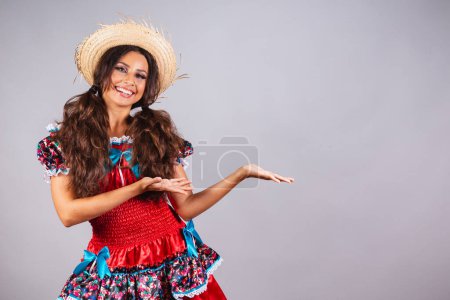 Foto de Mujer brasileña, con ropa de fiesta de junio. Festival de San Juan. Introduciendo el producto en el lateral. Publicidad o texto. - Imagen libre de derechos