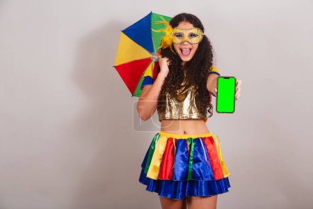 Foto de Jovencita adolescente, brasileña, con ropa frevo, carnaval. con paraguas frevo. celebración de smartphone con pantalla croma verde. - Imagen libre de derechos