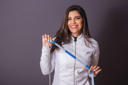 Photo for Horizontal photo. brazilian woman with medical coat, nutritionist. measuring tape. slimming. - Royalty Free Image