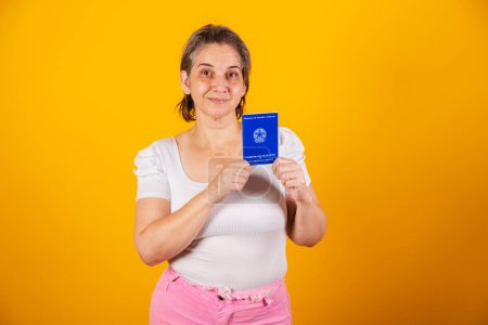 Photo for Adult Brazilian woman, holding work and social security card, Brazilian document for formal work. - Royalty Free Image