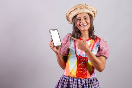Foto de Mujer brasileña vistiendo ropa de campo, fiesta So Joo, fiesta Junina. Con smartphone mostrando pantalla blanca en croma - Imagen libre de derechos