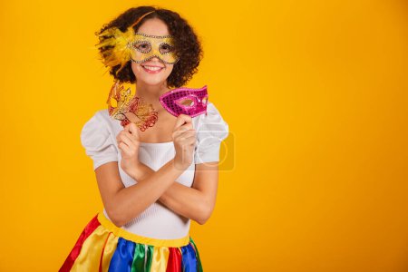 Photo for Beautiful Brazilian woman, dressed in carnival clothes, colorful skirt and white shirt. frevo umbrella, holding carnival masks. - Royalty Free Image