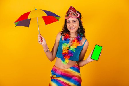 Téléchargez les photos : Belle femme brésilienne en vêtements de carnaval tenant smartphone avec écran vert. - en image libre de droit