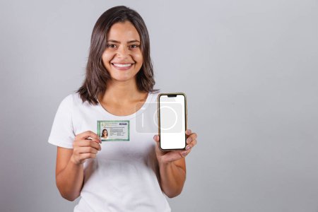 Foto de Mujer brasileña, con cédula de identidad brasileña, RG, documento. Smartphone, pantalla blanca para anuncios. - Imagen libre de derechos