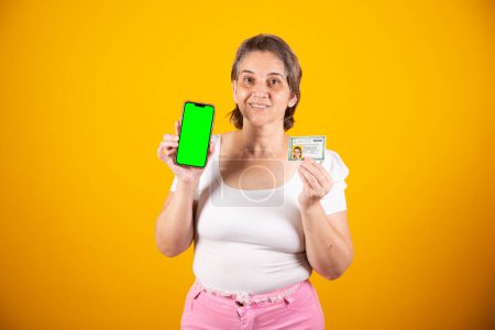 Téléchargez les photos : Femme Brésilienne adulte titulaire d'une carte d'identité, d'une carte d'identité et d'un smartphone avec écran vert - en image libre de droit