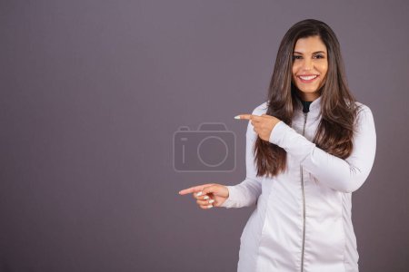 Téléchargez les photos : Photo horizontale. femme brésilienne avec manteau médical, nutritionniste. afficher une annonce sur la gauche. - en image libre de droit