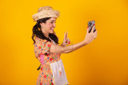 Foto de Hermosa mujer brasileña, con ropa de fiesta junina, tomando autorretrato con teléfono inteligente. - Imagen libre de derechos