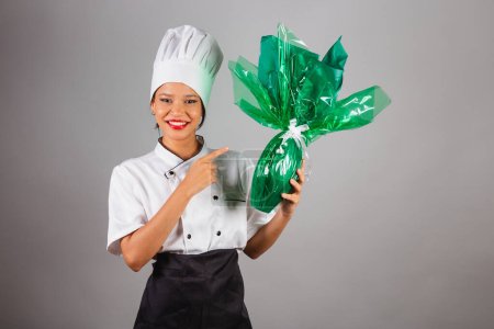 Téléchargez les photos : Chef cuisinier, cuisinier brésilien, du Nord-Est, tenant un œuf de Pâques, chocolat en forme d'œuf, spécialiste dans la préparation de chocolats. - en image libre de droit