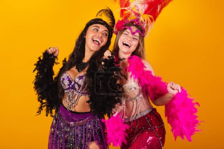 two Brazilian female friends, in carnival outfits, dancing