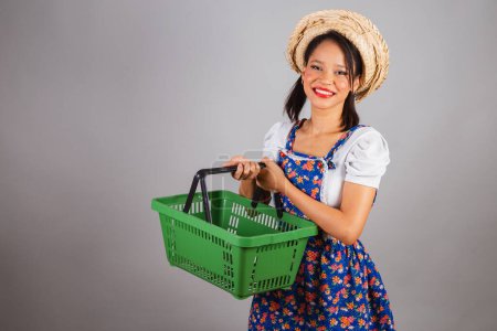 Photo for Brazilian woman, northeastern, with June party clothes, straw hat. holding market basket,shopping for So Joo party. - Royalty Free Image