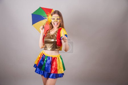 Foto de Mujer rubia brasileña, vestida con ropa frevo, máscara de carnaval, bailando con paraguas frevo. - Imagen libre de derechos