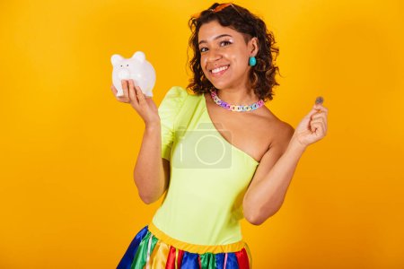 Téléchargez les photos : Belle femme brésilienne afro-américaine en vêtements de carnaval tenant tirelire et pièce. - en image libre de droit