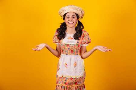Foto de Hermosa brasileña, con ropa de fiesta de junio, riendo, con los brazos abiertos, bienvenida. - Imagen libre de derechos