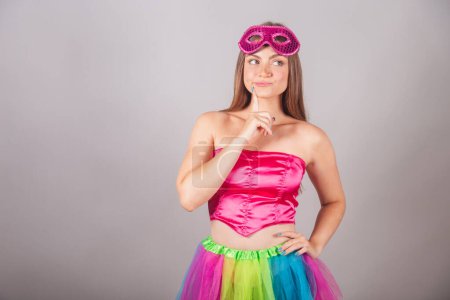 Téléchargez les photos : Femme blonde brésilienne vêtue de vêtements de carnaval rose. portant un mascara, pensant. - en image libre de droit