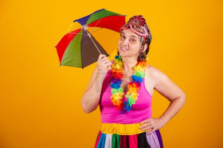 Téléchargez les photos : Femme adulte dans des vêtements de carnaval, souriant à la caméra avec tenant parasol coloré. - en image libre de droit