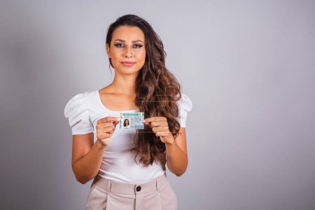Photo for Brazilian woman, brown hair, holding driver's license, Brazilian document. - Royalty Free Image