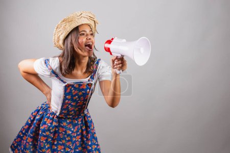 Foto de Mujer brasileña vistiendo ropa de campo, fiesta So Joo, fiesta Junina. con megáfono anunciando promociones y anuncios. - Imagen libre de derechos