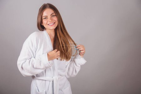 Photo for Brazilian blonde woman showing wonderful hair. Wearing a bathrobe. Messing with hair, hair with movement. - Royalty Free Image