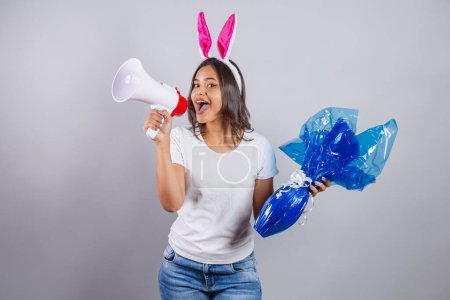 Téléchargez les photos : Femme brésilienne avec des oreilles de lapin de Pâques tenant mégaphone et oeuf de Pâques. - en image libre de droit