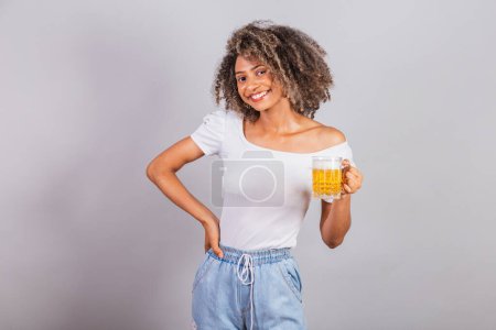 Téléchargez les photos : Belle femme brésilienne noire en vêtements décontractés tenant verre de bière. - en image libre de droit