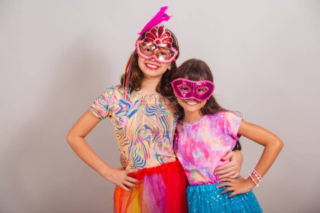 Téléchargez les photos : Deux enfants brésiliens, filles, vêtus de vêtements de carnaval, étreignant et souriant à la caméra. - en image libre de droit