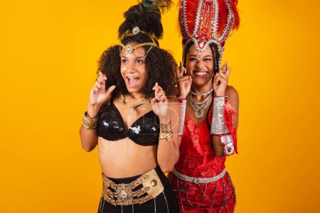 Téléchargez les photos : Deux amies brésiliennes, vêtues de carnaval. acclamations, souhait, doigts croisés. - en image libre de droit