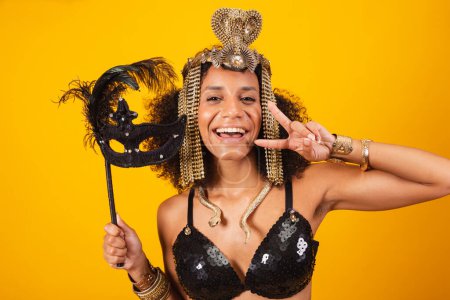 Foto de Hermosa mujer brasileña negra, en ropa de carnaval Cleopatra, sosteniendo máscara de carnaval, tomando retrato de cerca. - Imagen libre de derechos
