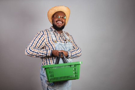 Photo for Brazilian black man wearing country clothes from festa junina,festa de so joo. arrai, holding market basket, shopping, promotions. - Royalty Free Image