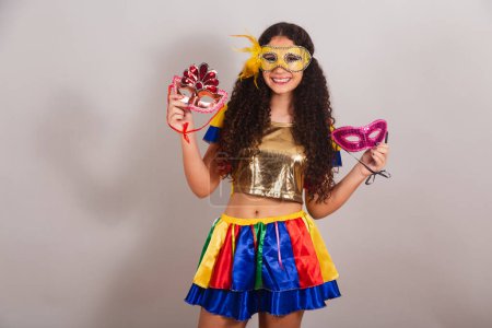 Téléchargez les photos : Jeune adolescente, brésilienne, avec des vêtements frevo, carnaval. masques de carnaval tenant. - en image libre de droit