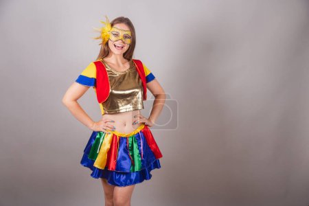 Téléchargez les photos : Femme blonde brésilienne, vêtue de vêtements frevo, masque de carnaval et la main sur sa taille. - en image libre de droit