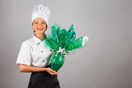 Photo for Head chef, Brazilian cook, from the Northeast, holding an Easter egg, chocolate in the shape of an egg, specialist in the preparation of chocolates. - Royalty Free Image