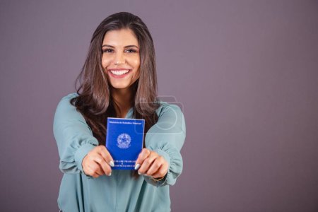 Photo for Horizontal photo. Beautiful Brazilian woman, with casual clothes, Jeans and green shirt. holding work card and social security. Document. - Royalty Free Image
