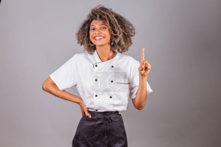 Téléchargez les photos : Jeune Brésilienne noire, cuisinière, chef cuisinière, portant l'uniforme de restaurant. avoir des idées. - en image libre de droit