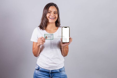 Photo for Brazilian woman, with Brazilian identity card, RG, document. Smartphone, white screen for advertisements. - Royalty Free Image
