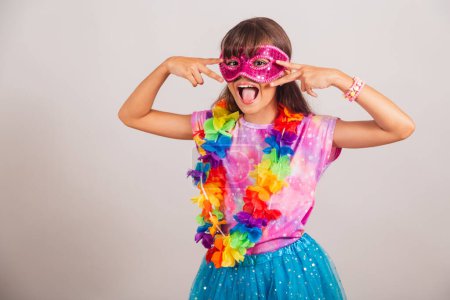 Téléchargez les photos : Belle fille brésilienne, enfant, habillée pour le carnaval au Brésil. avec masque de carnaval, danse. - en image libre de droit