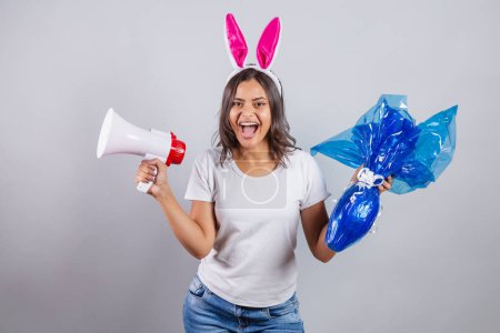 Téléchargez les photos : Femme brésilienne avec des oreilles de lapin de Pâques tenant mégaphone et oeuf de Pâques. - en image libre de droit
