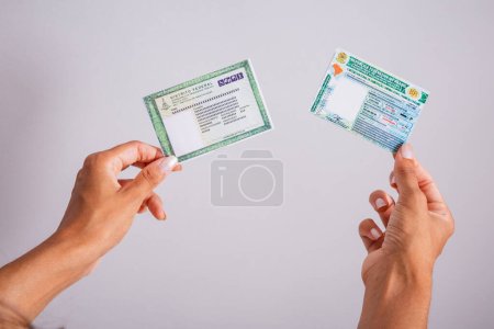 Hands holding driver's license and identity card. Brazilian documents.