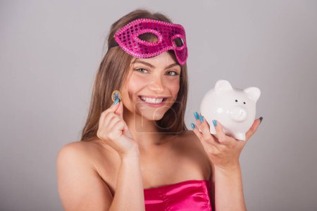 Foto de Mujer rubia brasileña vestida con ropa de carnaval rosa. sosteniendo alcancía y moneda. Ahorra dinero. invertir. - Imagen libre de derechos