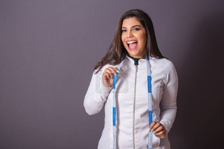 Photo for Horizontal photo. brazilian woman with medical coat, nutritionist. measuring tape. slimming. - Royalty Free Image