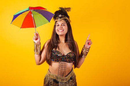 Téléchargez les photos : Belle femme brésilienne en vêtements de carnaval d'or dansant avec parapluie - en image libre de droit